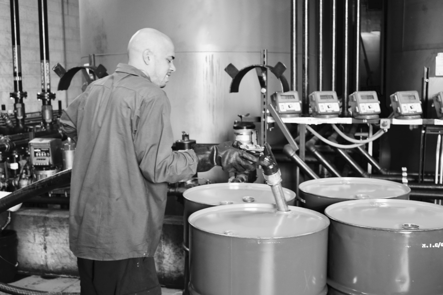 Worker filling 55 gallon drums from bulk storage tanks